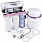 Angled view of Aqua Cares RO purifier with clear housing, storage tank, faucet, wrenches and fittings