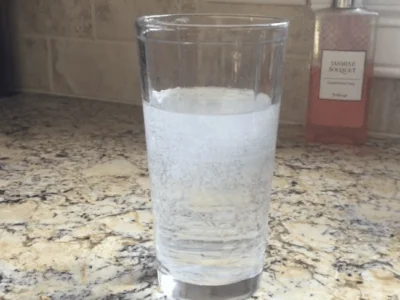 Small air bubbles visible in a glass of water on a kitchen countertop