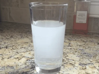 Glass containing cloudy white water on a kitchen countertop