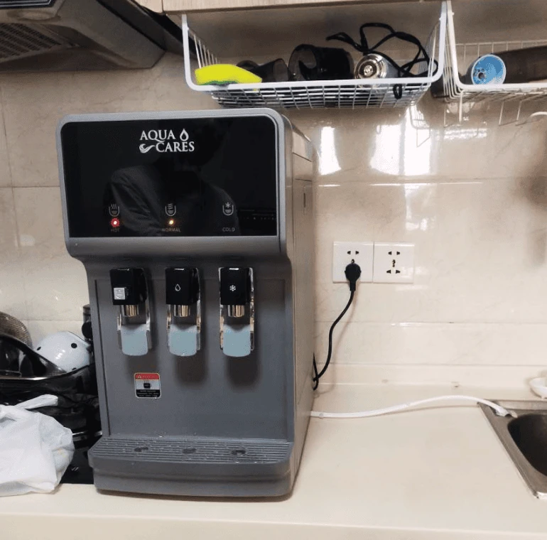 Countertop hot and cold water dispenser installed beside a kitchen sink