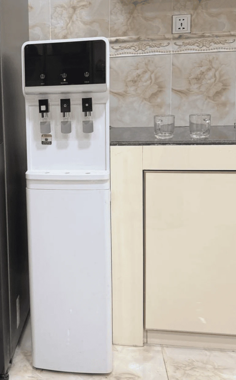 Floor-standing hot and cold water dispenser installed in a home kitchen